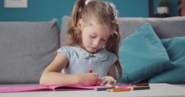 Mavi elbiseli güzel kız çizim için renkli kalemler kullanıyor.