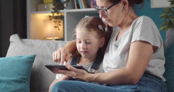 Mãe e filha usando tablet enquanto sentado no sofá — Vídeo de Stock