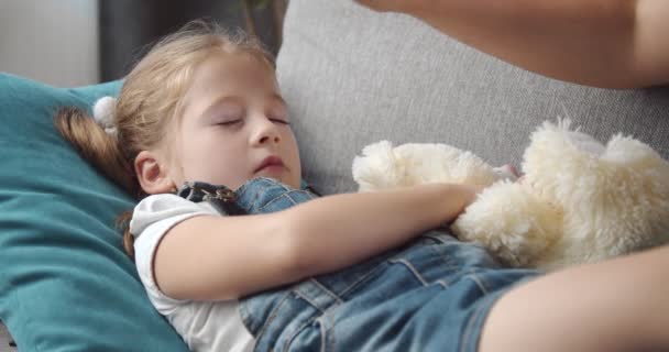 Chory dzieciak śpi na kanapie, podczas gdy matka dotyka czoła — Wideo stockowe