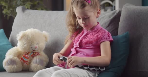 Beautiful girl sitting on couch and playing with puzzles — Stock Video