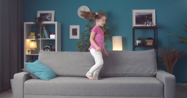 漂亮的孩子，戴着马尾辫，在灰色的沙发上跳舞唱歌 — 图库视频影像
