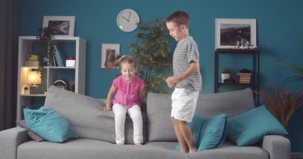 Energetic brother and sister jumping together on couch — Stock Video