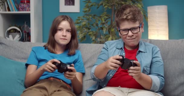 Wesoły chłopak i dziewczyna grają w gry wideo z joystickami — Wideo stockowe