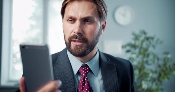 Bonito empresário usando smartphone para videochamada no trabalho — Vídeo de Stock