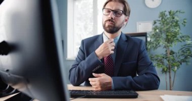 Yorgun adam bilgisayardaki uzun çalışma gününden sonra kravatını gevşetti