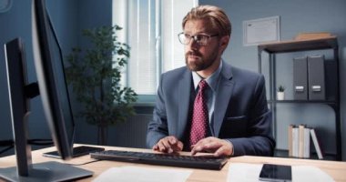 Masada oturan ve bilgisayarda yazan yakışıklı adam.