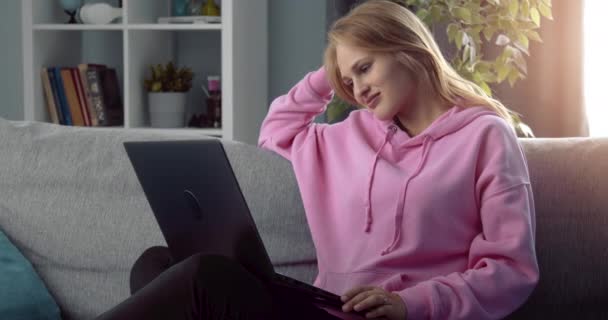 Femme détendue assise sur un canapé confortable et utilisant un ordinateur portable — Video