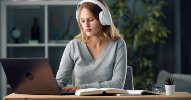 Estudante usando fones de ouvido sem fio e laptop para estudar — Vídeo de Stock