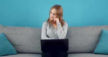 Dizüstü bilgisayarla koltukta oturan bir kadın yan bakıyor.