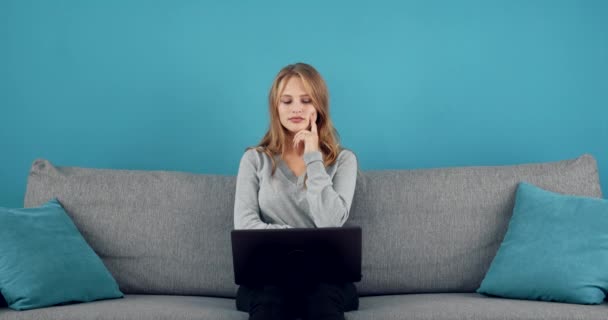 Mujer reflexiva mirando la pantalla de la computadora en el sofá — Vídeos de Stock