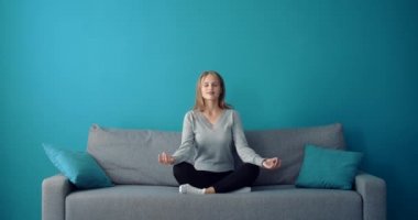 Rahat kız kanepede gözleri kapalı meditasyon yapıyor.