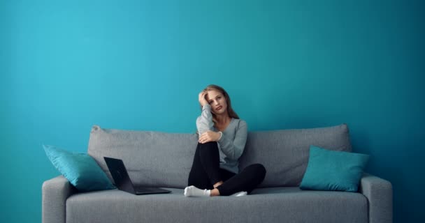 Zasněný dívka sedí na gauči a dává si pauzu od notebooku — Stock video