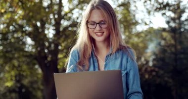 Mutlu kadın dışarıda bilgisayarında görüntülü konuşma yapıyor.