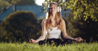 Kulaklıklı rahat kadın doğa üzerine meditasyon yapıyor.
