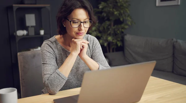 Kadın dizüstü bilgisayardan bir şey izliyor.