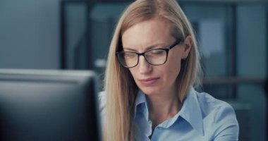 İş kadını masada oturuyor ve bilgisayar kullanıyor.