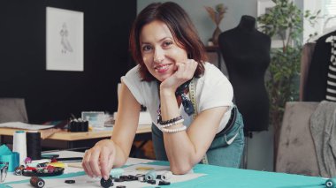 Kadın terzi masanın üzerine eğiliyor.