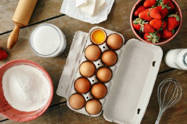 Üstten görünüm ham maddeler çilek pasta ya da kek (yumurta, un, süt, şeker, çilek), ahşap masa üzerine düz yemek pişirmek için yatıyordu. Fırın arka plan. Çilekli pasta tarifi