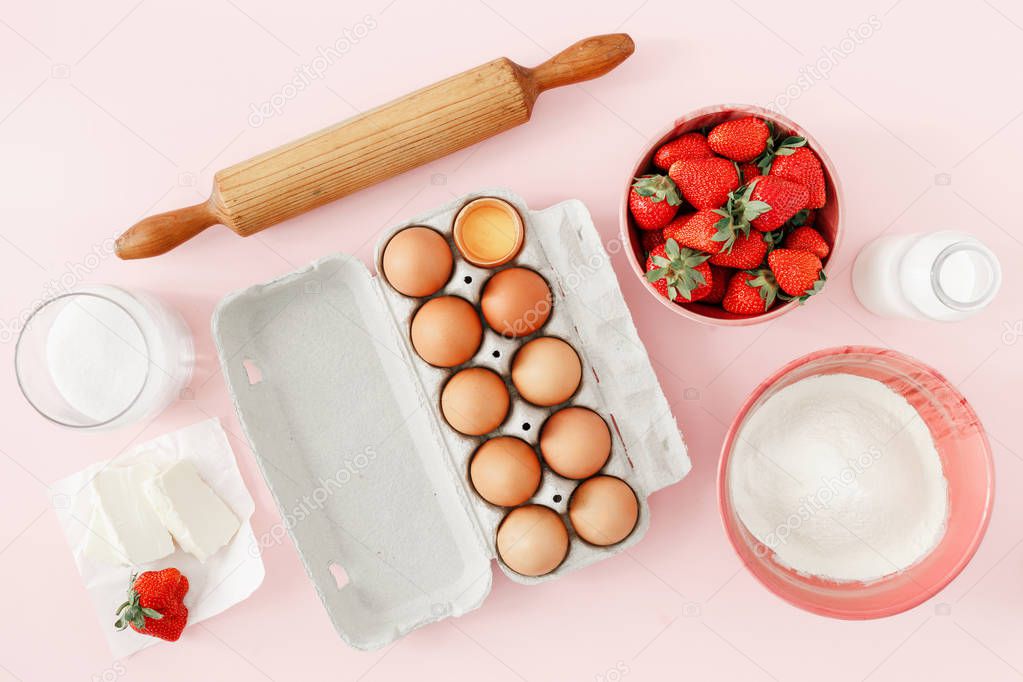 Flat lay raw ingredients for cooking strawberry pie or cake on pink background  (eggs, flour, milk, sugar, strawberry), top view. Bakery background. Recipe for strawberry pie