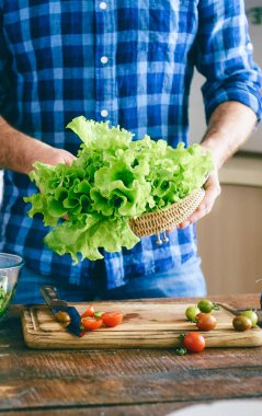 Erkek mutfak güneşli akşam taze marul yaprağı evde tutan eller. Sağlıklı gıda kavramı
