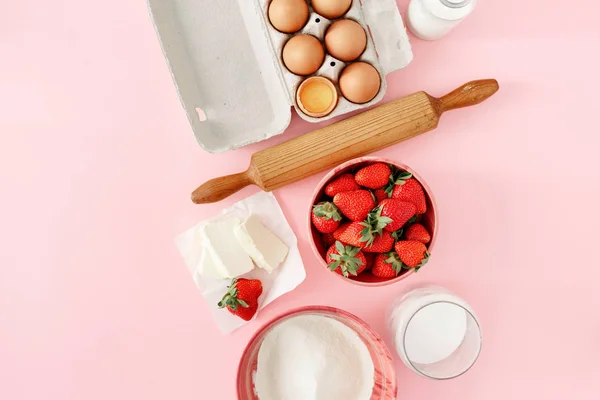 Ingredients for cooking strawberry pie or cake on white table with free space for your text or object. Flat lay, top view. Eggs, flour, milk, sugar, strawberry, top view. Bakery background. Recipe for strawberry pie. Rustic style
