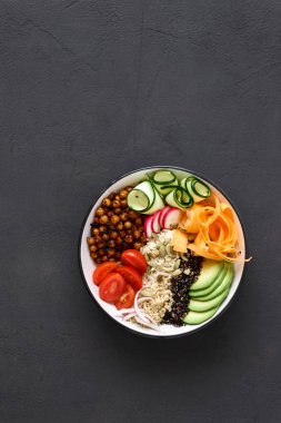 Vejetaryen Buda kase. Temiz ve dengeli sağlıklı gıda kavramı. Pirinç, baharatlı nohut, siyah ve beyaz quinoa, avokado, havuç, kabak, turp, domates kopya alanı, üstten görünüm ile koyu arka plan üzerinde