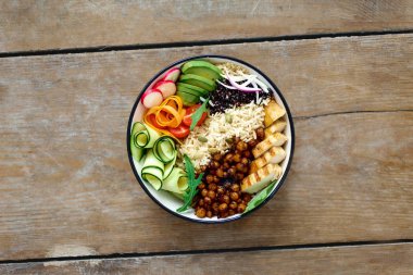 Üst Buda kase görüntüleyin. Temiz ve dengeli sağlıklı gıda kavramı. Tavuk ızgara biftek, pirinç, baharatlı nohut, siyah ve beyaz quinoa, avokado, havuç, kabak, turp, domates ahşap tablo
