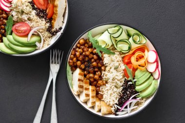 Sağlıklı temiz ve dengeli beslenme kavramı. Tavuk ızgara biftek, pirinç, baharatlı nohut, siyah ve beyaz quinoa, avokado, havuç, kabak, turp, domates Buda kase koyu arka plan üzerinde üstten görünüm