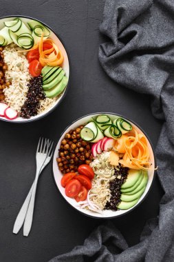 İki vejetaryen Buda kase. Temiz ve dengeli sağlıklı gıda kavramı. Pirinç, baharatlı nohut, siyah ve beyaz quinoa, avokado, havuç, kabak, turp, domates koyu arka plan, üstten görünüm