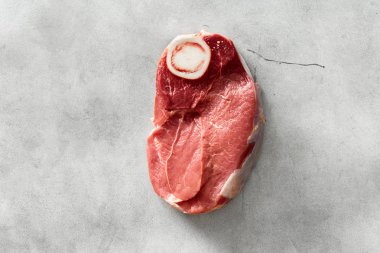 Ham sığır eti kemik beyaz beton arka planda, üstten görünüm