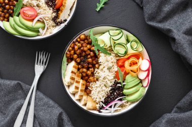 İki Buda kase. Temiz ve dengeli sağlıklı gıda kavramı. Tavuk ızgara biftek, pirinç, baharatlı nohut, siyah ve beyaz quinoa, avokado, havuç, kabak, turp, domates koyu arka plan, üstten görünüm