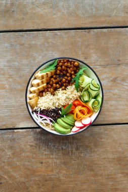 Tavuk ızgara biftek, pirinç, baharatlı nohut, siyah ve beyaz quinoa, avokado, havuç, kabak, turp, domates ahşap masa üzerinde. Üst Buda kase görüntüleyin. Temiz ve dengeli sağlıklı gıda kavramı