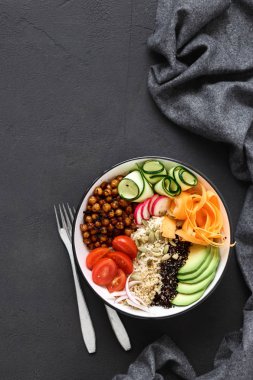 Pirinç, baharatlı nohut, siyah ve beyaz quinoa, avokado, havuç, kabak, turp, domates kase koyu arka plan üzerinde