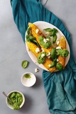 plaka tatlı kızarmış Mısır ve fesleğen sos ile mavi masa örtüsü, üstten görünüm üzerinde beyaz peynir ile