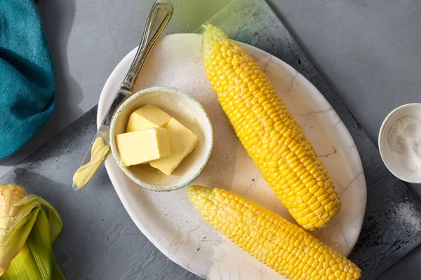 tereyağı ve tuz gri arka plan, üstten görünüm üzerinde ham tatlı Mısır ile plaka 