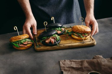 Adam ahşap tutarak ızgara sığır etli farklı burger kurulu