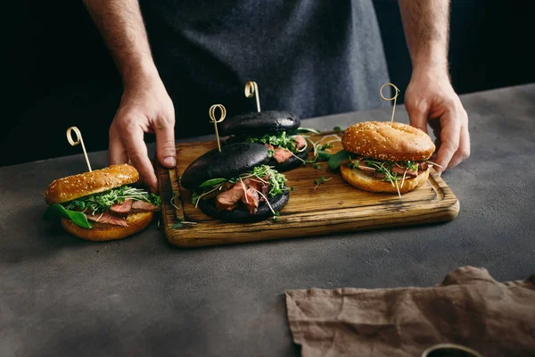 Adam ahşap tutarak ızgara sığır etli farklı burger kurulu