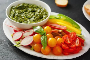 Siyah taş zemin üzerine çiğ sebze aperatif ve pesto sosu. Sağlıklı yemek
