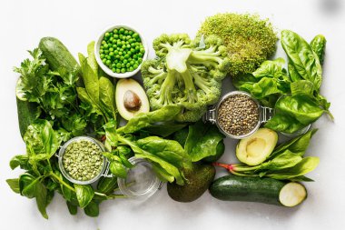 Ayarla çiğ sağlıklı gıda temiz vejetaryenler için yeme sebze ve tahıl ürünleri protein kaynağıdır: salatalık, lucerne, kabak, ıspanak, fesleğen, yeşil bezelye, avokado, brokoli, kireç ve yeşil mercimek beyaz üzerine beton arka plan, üstten görünüm