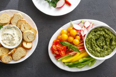 Sağlıklı snack kavramı. Çiğ sebze ve siyah taş zemin üzerine sarımsak soslu pesto sos ekmek croutons. Vejetaryen Sağlıklı yiyecekler üstten görünüm