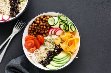 Clean and balanced healthy food concept. Two vegetarian buddha bowl. Rice, spicy chickpeas, black and white quinoa, avocado, carrot, zucchini, radish, tomatoes on dark background close up, top view clipart