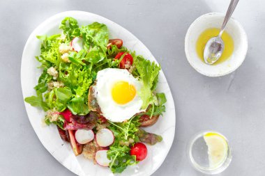 Tabak taze salata quinoa, sos, kızarmış yumurta ve gri beton zemin üstten görünüm cam limon suyu ile. Temiz sağlıklı yemek yeme