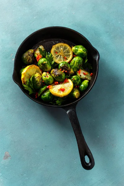 Healthy Vegetarian Food. Cast iron frying pan with fried broccoli on blue stone background, top view