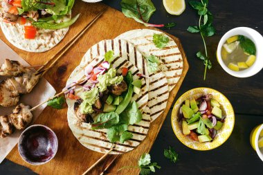 Üstten görünüm tacos ızgara tavuk koyu arka plan üzerinde sebze salsa, guacamole sos ile