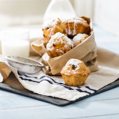 Kuru üzüm ve süt ile mavi ahşap masa üzerine pudra şekeri ile ev yapımı cupcakes kapatın 