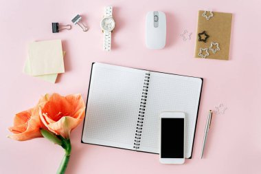 Düz yatıyordu ev ofis resepsiyon masası. Açık defter, smartphone, çiçek ve kişisel aksesuar pastel pembe kadınsı çalışma alanı