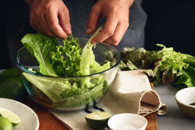 Adam yeşil detoks marul salatası yemek pişiriyor. Sağlıklı gıda kavramı
