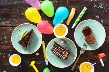 Çikolatalı kek ve dekorasyon parti kahverengi ahşap masa düz üzerinde yatıyordu. Üstten görünüm Çocuk Doğum günü tablo şenlikli gıda ile