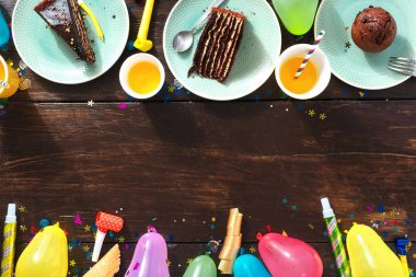 Üstten görünüm Çocuk Doğum günü tablo kavramı. Çerçeve çikolatalı kek ve dekorasyon partisi düz kahverengi ahşap zemin üzerinde yatıyordu