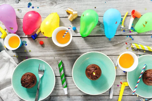 Flat lay children birthday table. Chocolate muffins and decoration party on wooden background top view
